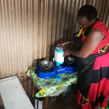 Mary Omweno fixing ethanol fuel canister into a cooker ready to warm food for her customers (1)
