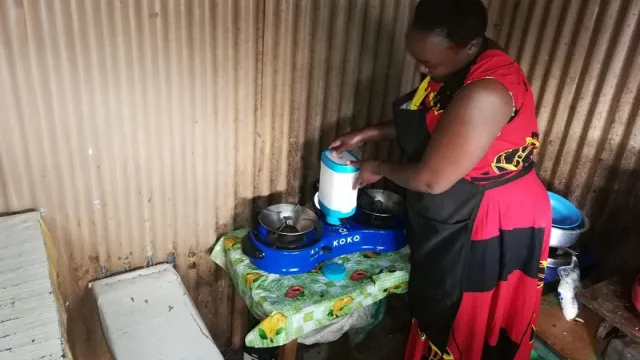 Mary Omweno fixing ethanol fuel canister into a cooker ready to warm food for her customers (1)