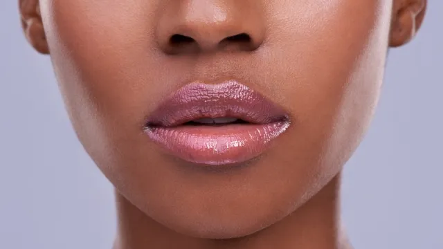 Cropped shot of a young woman's mouth against a purple background